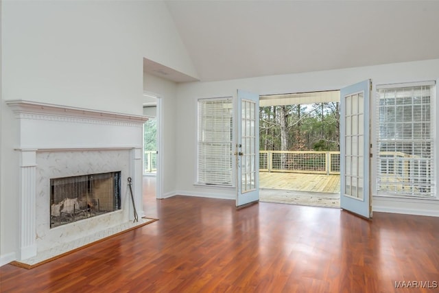 unfurnished living room featuring high vaulted ceiling, wood finished floors, french doors, a premium fireplace, and baseboards