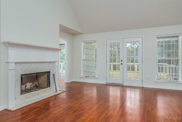 unfurnished living room featuring high vaulted ceiling, wood finished floors, french doors, a fireplace, and baseboards