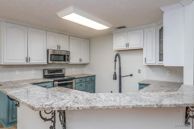 kitchen featuring visible vents, appliances with stainless steel finishes, a peninsula, white cabinets, and light stone countertops