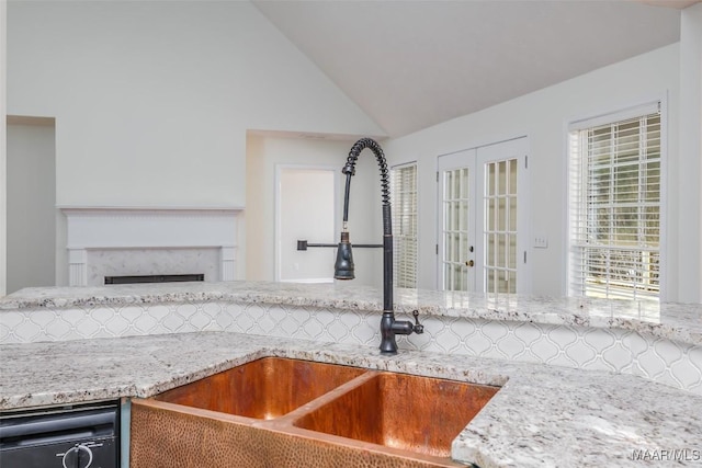 kitchen featuring light stone countertops, a premium fireplace, a sink, french doors, and dishwasher