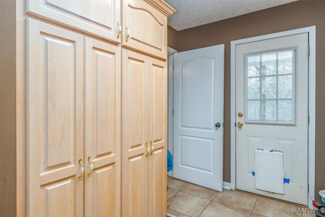 doorway to outside with light tile patterned flooring and a textured ceiling