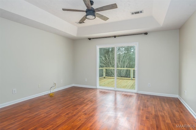 spare room featuring a raised ceiling, wood finished floors, and visible vents