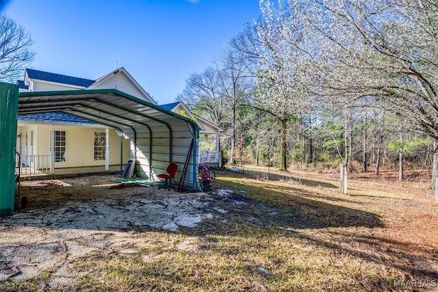 view of yard featuring a carport and dirt driveway