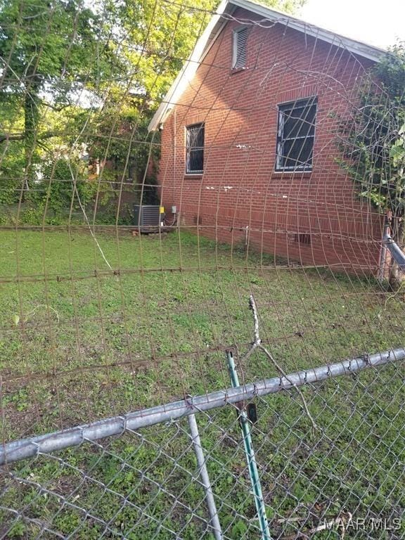 view of side of home with brick siding, a yard, and fence