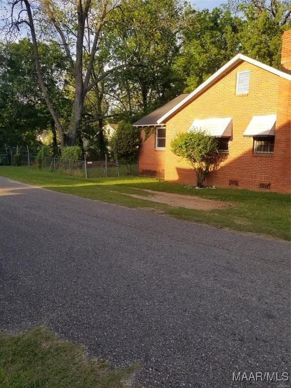 view of home's exterior featuring fence, brick siding, and a lawn