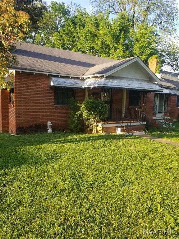 ranch-style home with brick siding, a porch, and a front lawn