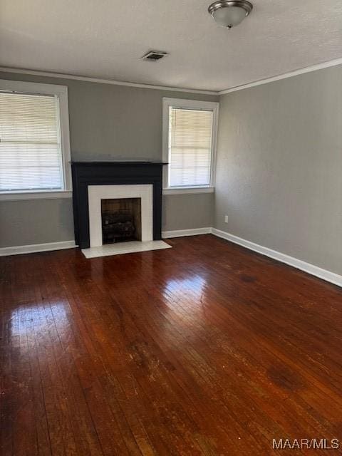 unfurnished living room with visible vents, a fireplace with flush hearth, hardwood / wood-style flooring, crown molding, and baseboards