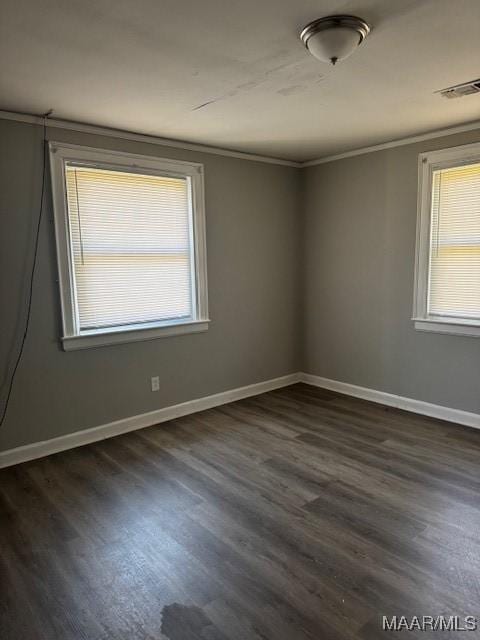 spare room with dark wood-style floors, plenty of natural light, baseboards, and ornamental molding