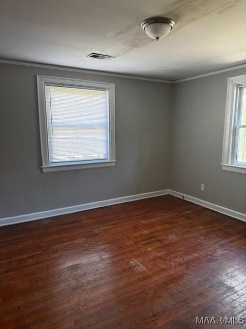 empty room featuring crown molding, baseboards, visible vents, and dark wood-type flooring