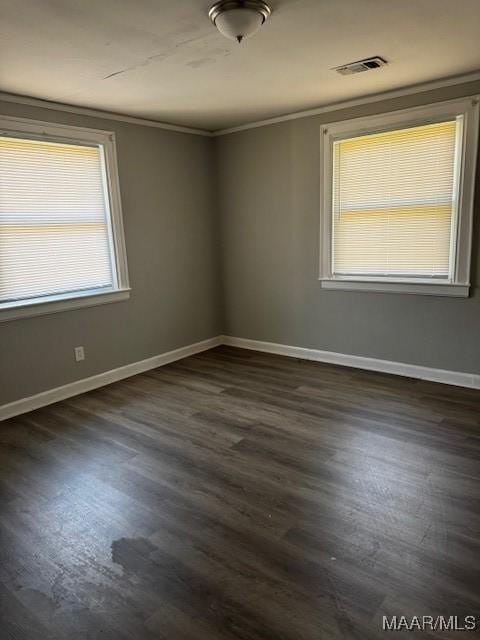 unfurnished room with crown molding, dark wood-style floors, baseboards, and visible vents