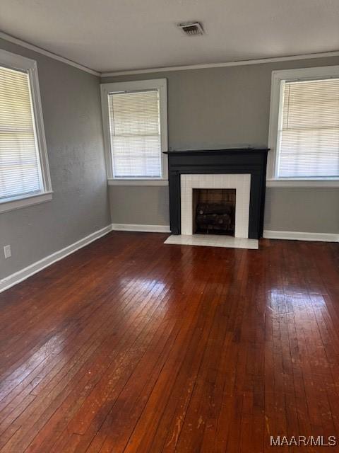 unfurnished living room with visible vents, a fireplace, hardwood / wood-style floors, and ornamental molding