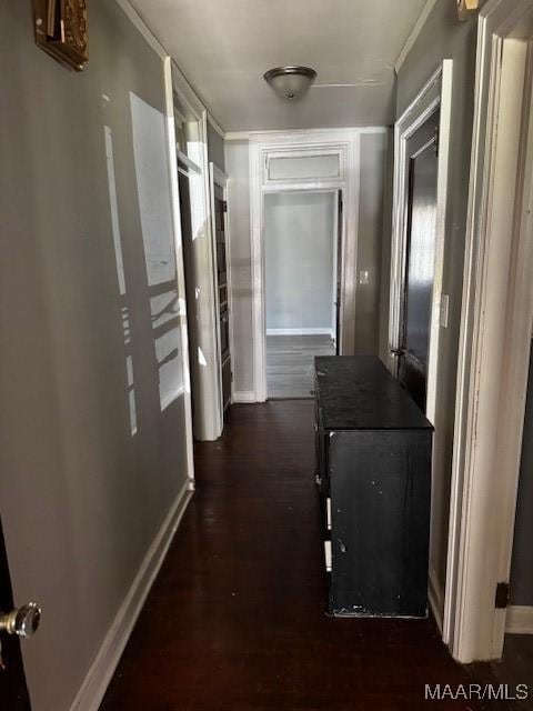 hallway featuring dark wood-style floors, crown molding, and baseboards