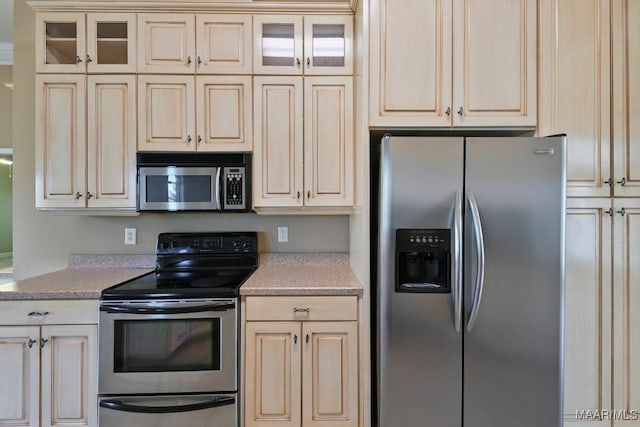 kitchen featuring stainless steel appliances, glass insert cabinets, and cream cabinetry