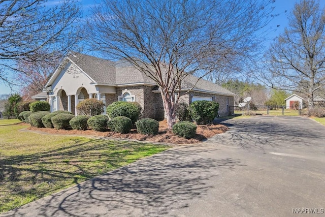 view of front of home featuring brick siding, fence, a front yard, a garage, and driveway