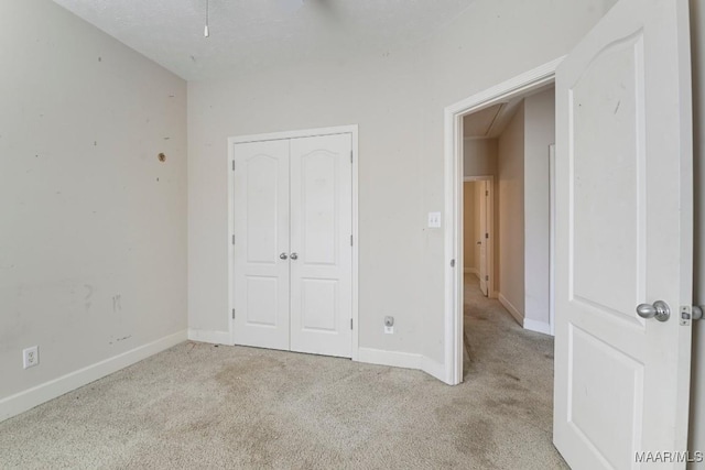 unfurnished bedroom with a closet, baseboards, carpet, and attic access