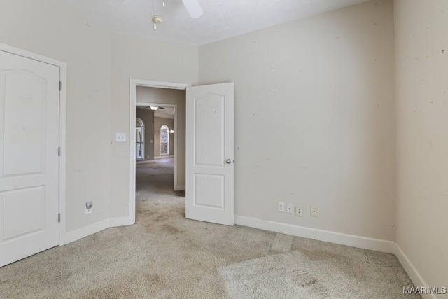 empty room with carpet flooring, a ceiling fan, and baseboards