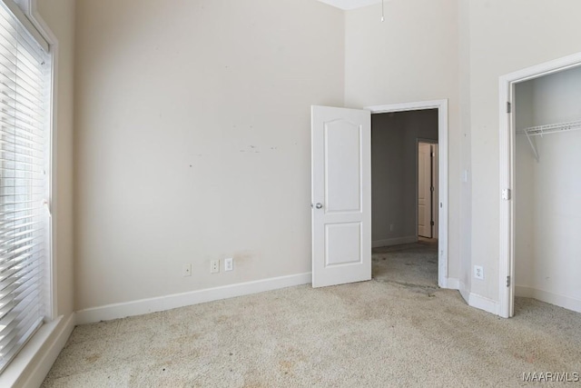 unfurnished bedroom with baseboards, carpet floors, and a closet