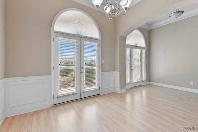 doorway with arched walkways, plenty of natural light, french doors, and an inviting chandelier