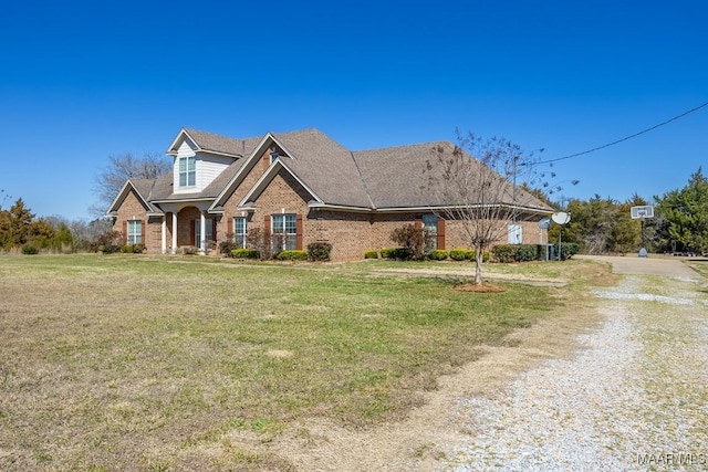 view of front facade featuring a front yard, brick siding, and driveway