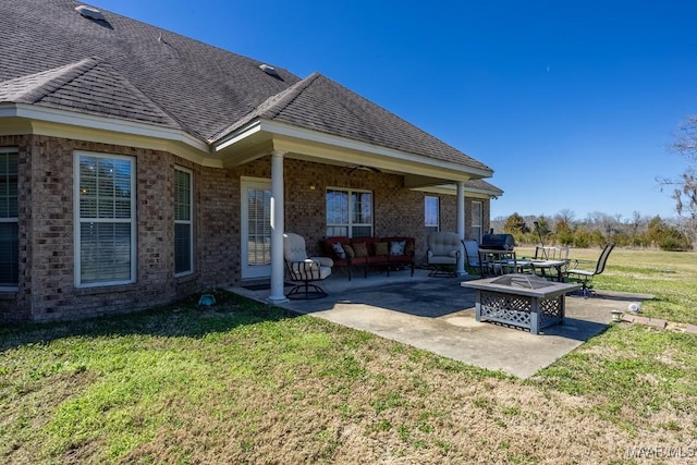 back of property featuring a yard, an outdoor fire pit, roof with shingles, and a patio area