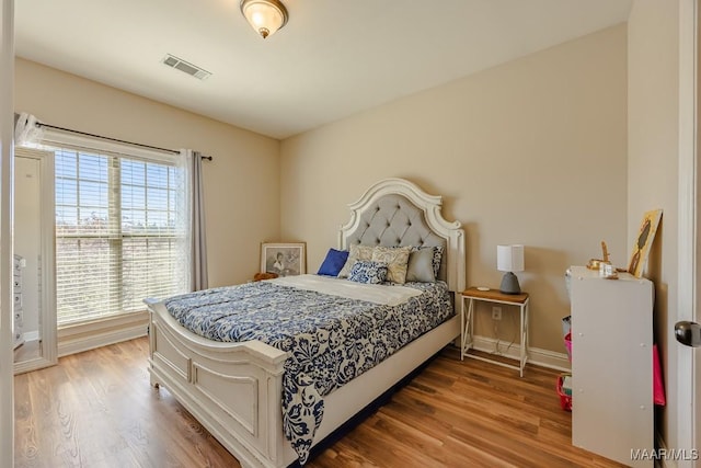 bedroom featuring visible vents, baseboards, and wood finished floors