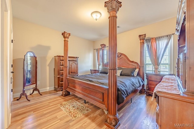 bedroom featuring baseboards, light wood-style flooring, and ornate columns