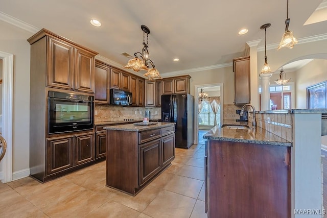 kitchen with a sink, a notable chandelier, black appliances, and dark stone countertops