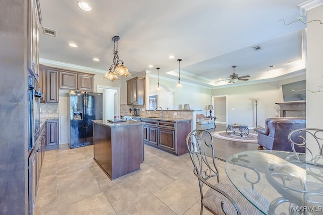 kitchen with visible vents, a kitchen island, a peninsula, black fridge with ice dispenser, and a sink