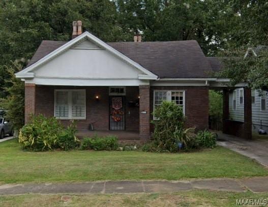 bungalow-style home with brick siding, covered porch, and a front lawn