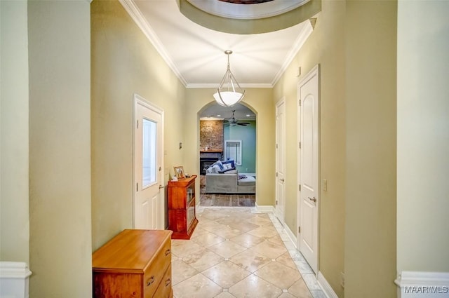 hallway featuring crown molding, light tile patterned floors, baseboards, and arched walkways