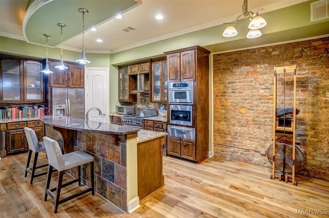 kitchen with range hood, visible vents, stainless steel appliances, decorative backsplash, and light wood-style floors