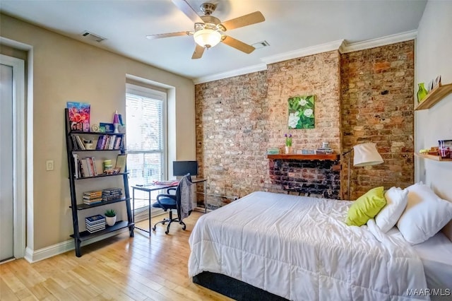 bedroom featuring visible vents, wood finished floors, brick wall, and crown molding