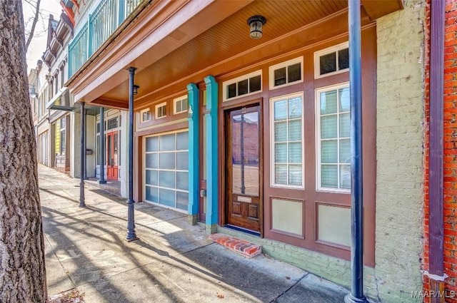 view of exterior entry with brick siding and a porch