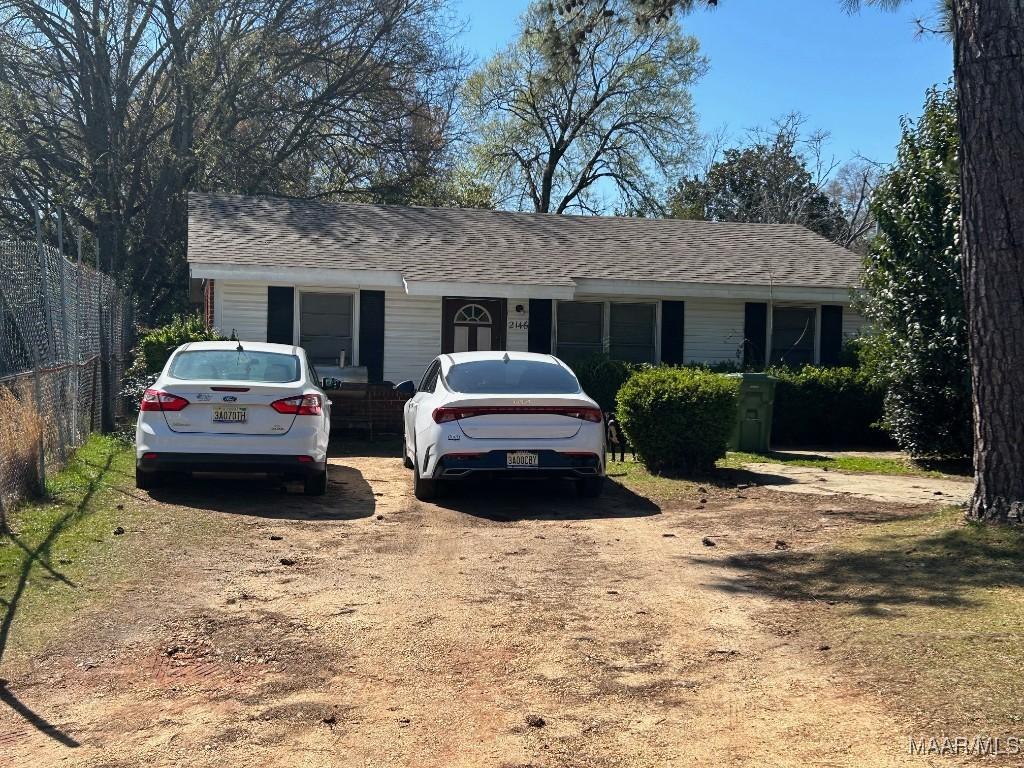 single story home featuring roof with shingles and fence