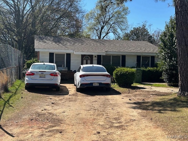 single story home featuring roof with shingles and fence