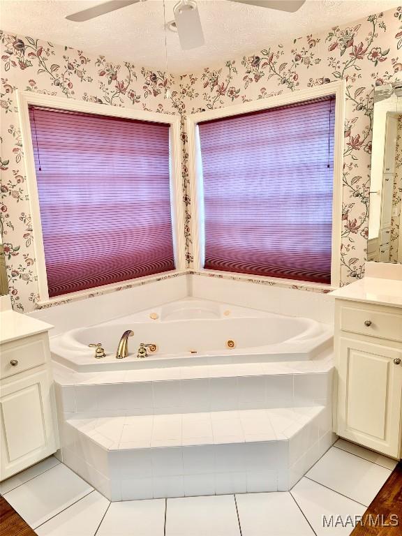 full bathroom with wallpapered walls, ceiling fan, vanity, a whirlpool tub, and a textured ceiling