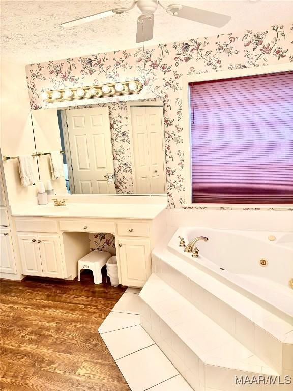 bathroom featuring a jetted tub, wallpapered walls, ceiling fan, wood finished floors, and vanity