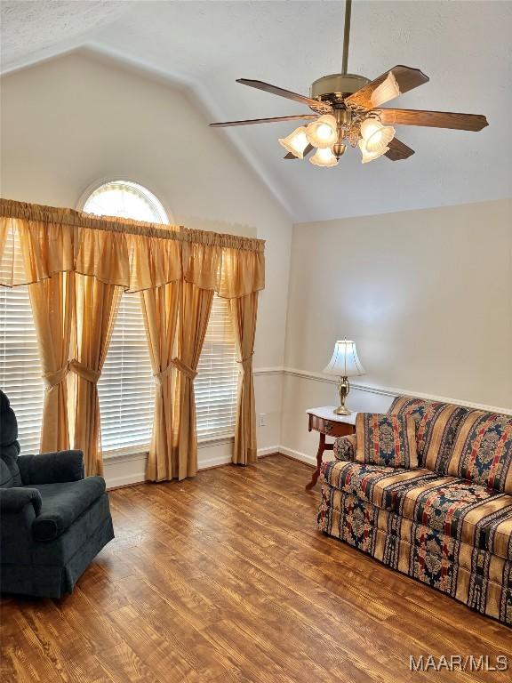 living area featuring lofted ceiling, wood finished floors, and ceiling fan