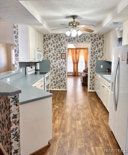 kitchen with white appliances, a textured ceiling, wood finished floors, and wallpapered walls