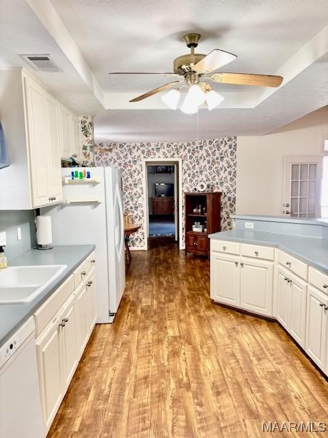 kitchen with visible vents, white appliances, wallpapered walls, and a tray ceiling