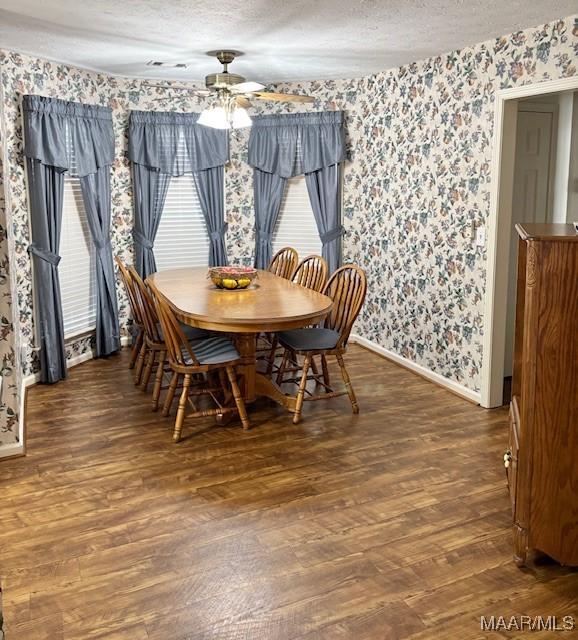 dining room featuring wallpapered walls, baseboards, wood finished floors, a textured ceiling, and a ceiling fan