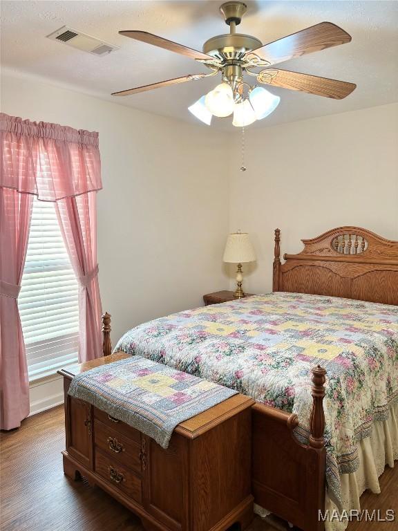 bedroom with visible vents, wood finished floors, and a ceiling fan