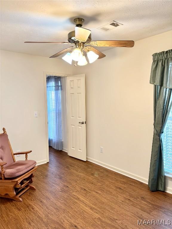 living area featuring visible vents, baseboards, wood finished floors, and a ceiling fan