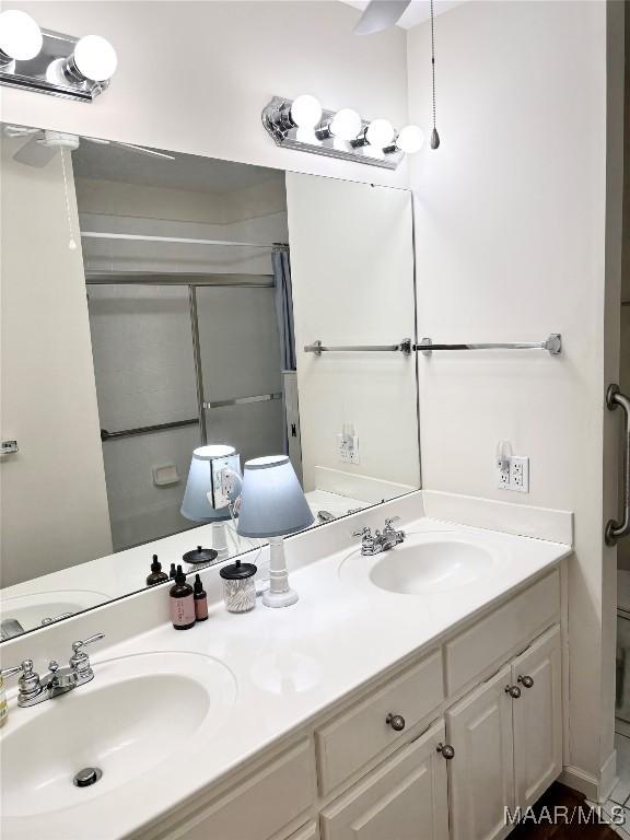 bathroom featuring double vanity, toilet, a shower with door, and a sink