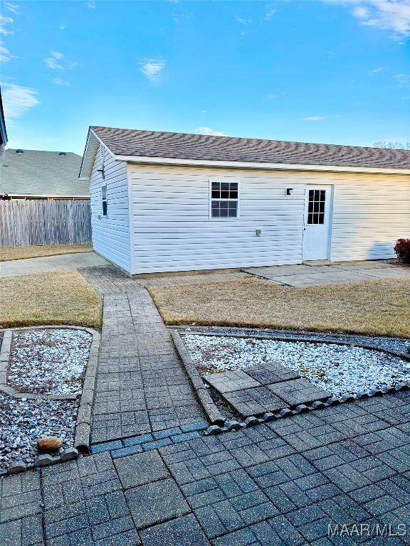 exterior space featuring a patio area, roof with shingles, and fence