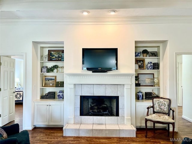 living area featuring built in features, dark wood-style floors, ornamental molding, a fireplace, and baseboards