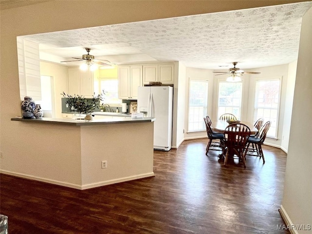 kitchen with white refrigerator with ice dispenser, a ceiling fan, dark wood-type flooring, healthy amount of natural light, and a textured ceiling