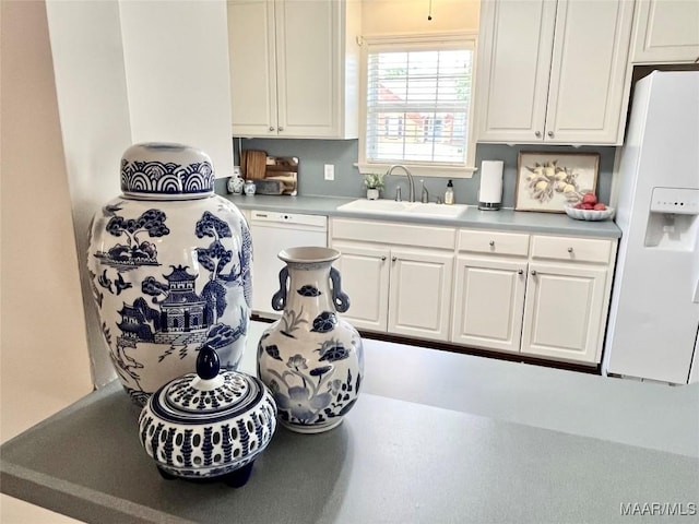 kitchen featuring white appliances, a sink, white cabinets, and light countertops