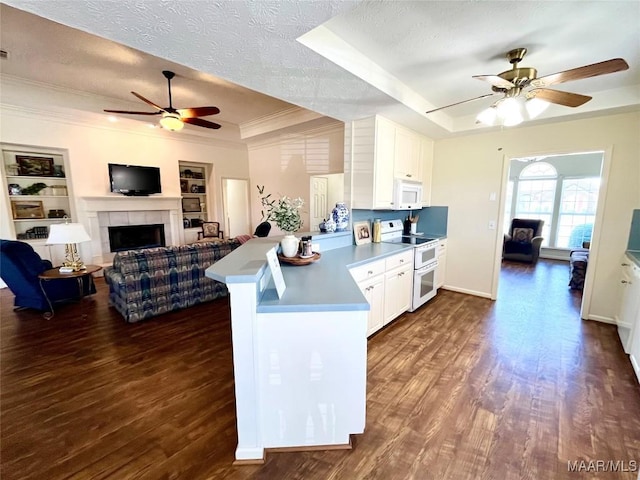 kitchen with white appliances, a ceiling fan, a raised ceiling, a peninsula, and a textured ceiling