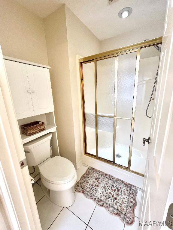 bathroom with tile patterned floors, a shower stall, and toilet